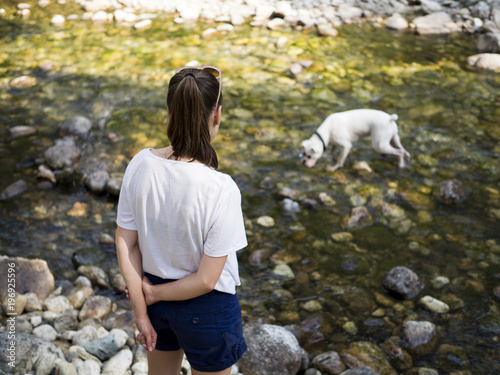 Young woman looking at her dog playing in the nature