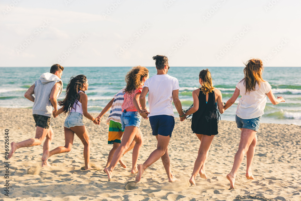 Multiracial group of friends running on the beach