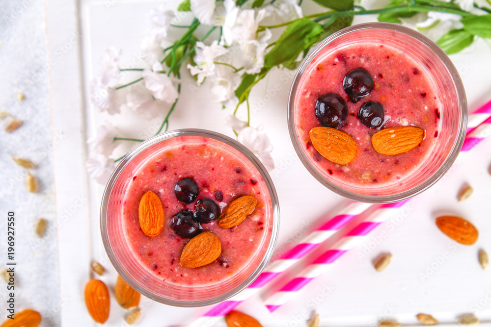 Blueberry smoothies of berries, banana and almonds in glasses with cocktail tubes on a white wooden board. Blueberry smoothies of berries, banana and almonds in glasses with cocktail tubes on a white wooden board.