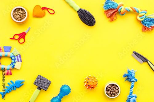 toys for pets and dry food on yellow background top view space for text photo
