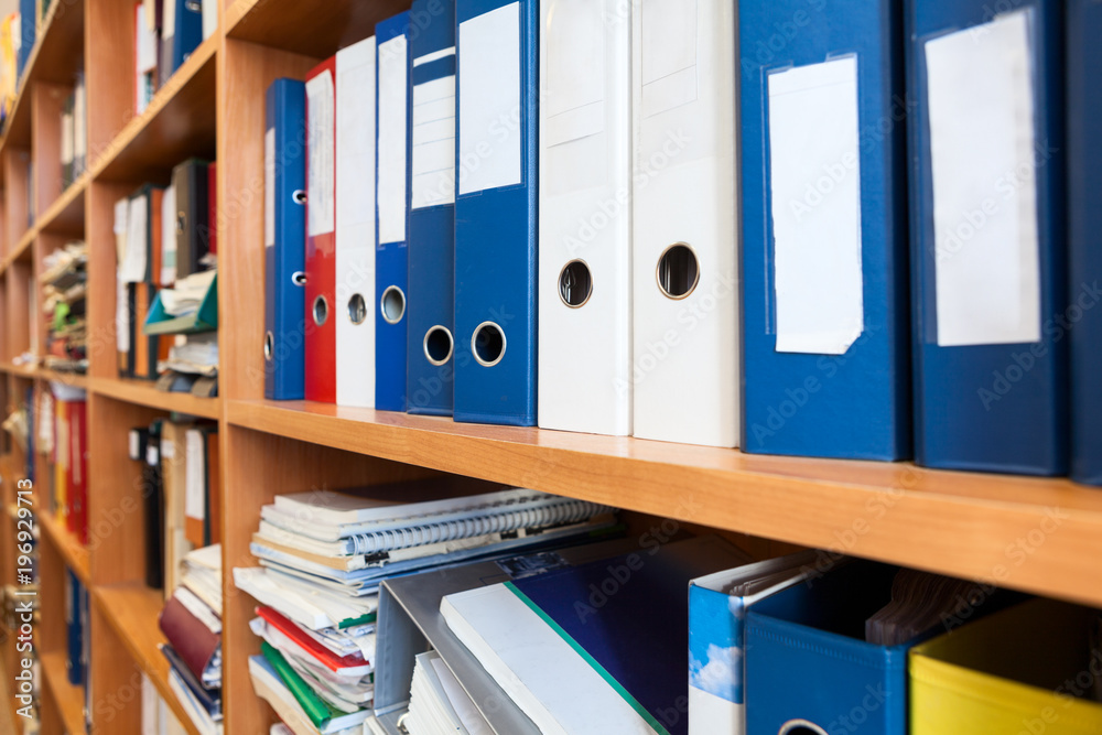 Perspective view at of colourful binders sorted on office shelves, archive