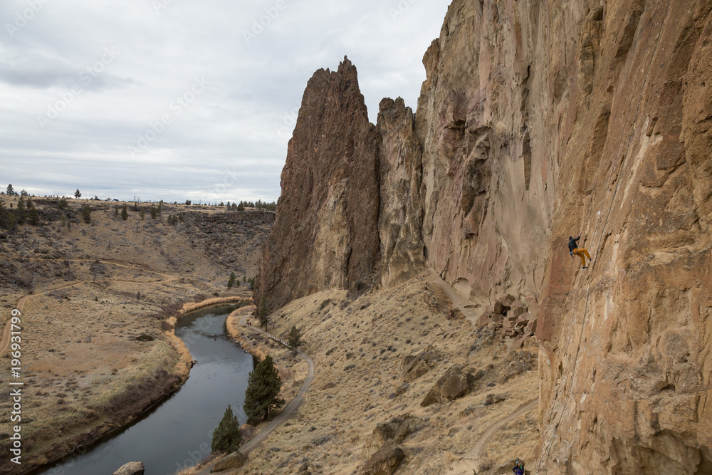 Beautiful landscape view of Smith Rock with a man rappelling down a steep cliff. Taken in Redmond, Oregon, USA.