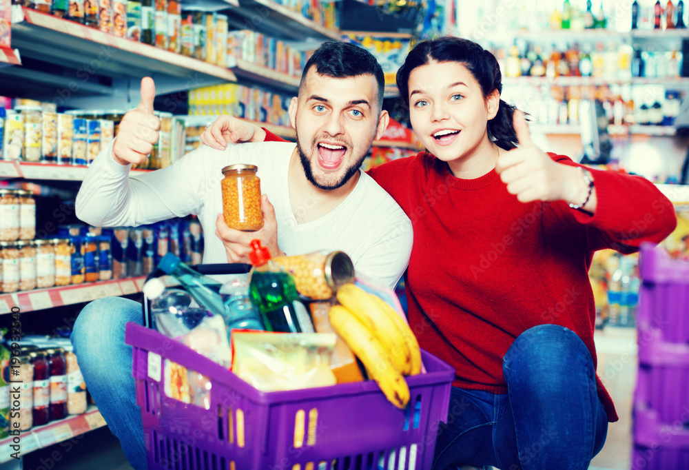 Couple standing near shelves with canned goods at store
