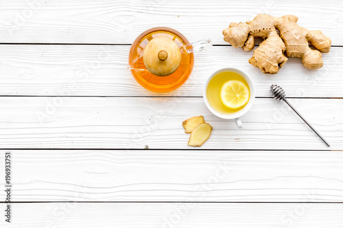 Warming tea with lemon and ginger. Cup, teapot, ginger root on white wooden background top view copy space
