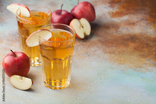 Two glasses of red Apple juice with mint and ice on an old rusty table. Soft drink on a blue background. With copy space