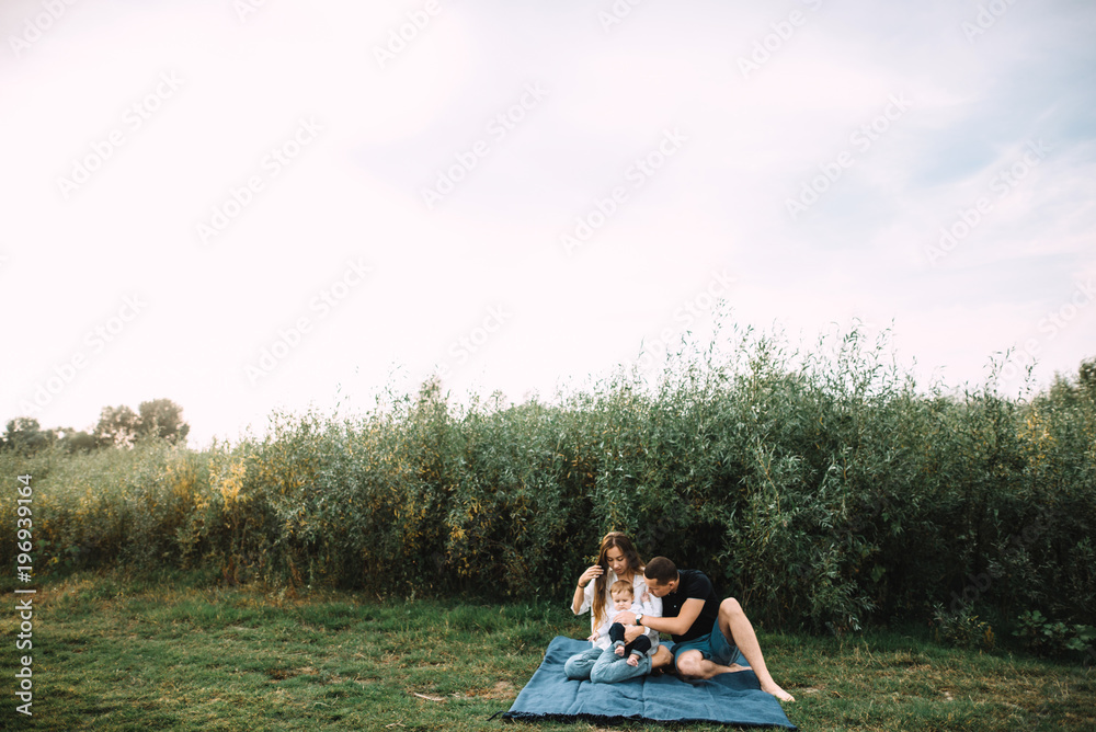 A happy family spends time together outside the city on the nature. Dad, mom and their little cute son A happy family spends time together outside the city on the nature. Dad, mom and their little cute son
