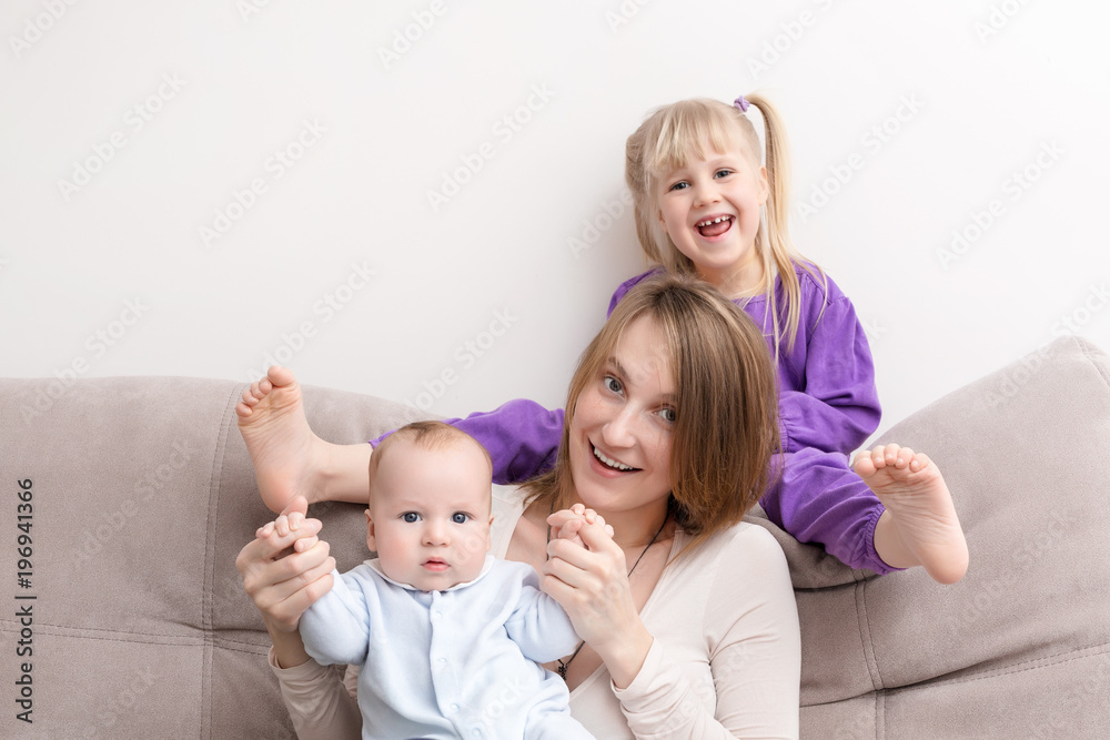 Mother with son and daughter having fun on sofa. Smiling and cheerful people. Happy family concept Mother with son and daughter having fun on sofa. Smiling and cheerful people. Happy family concept