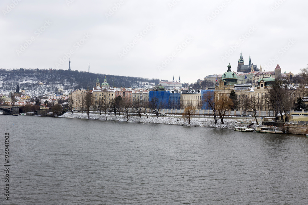 Obraz premium Snowy Prague Lesser Town with gothic Castle above River Vltava, Czech republic