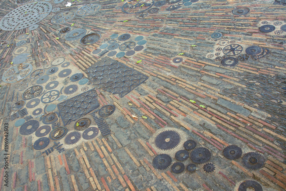 The surface of the floor of small parts. The pavement is made of automotive gears and pavers in Barcelona.