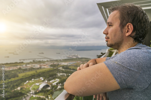 мужчина смотрит на залив с высоты небоскреба марина бэй сандс на фоне рассвета 