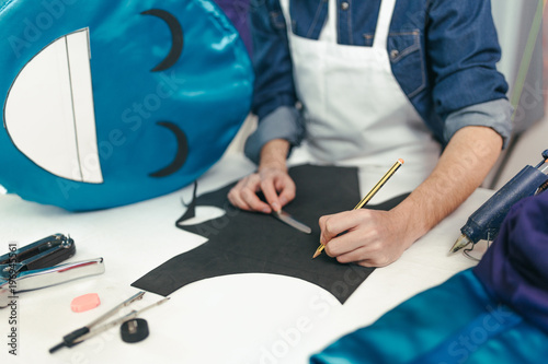 Close-up man working in the craft workshop. Young designer drawing on rubber eva. Customizing a carnival costume