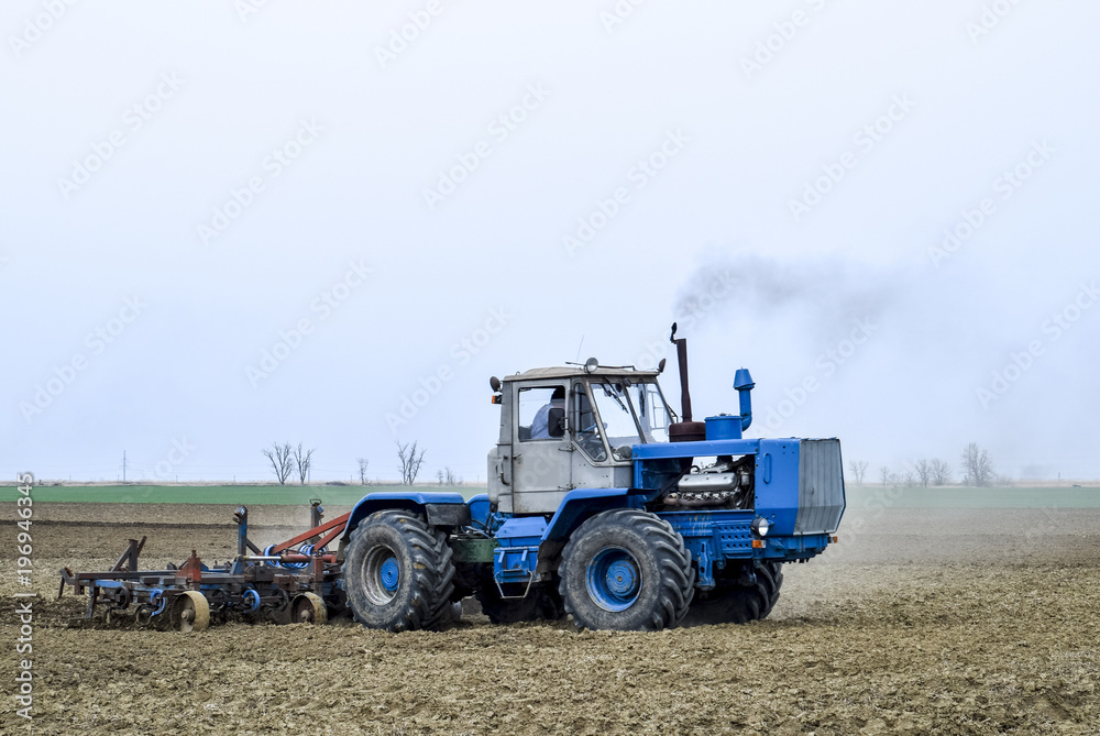 Lush and loosen the soil on the field before sowing. The tractor plows a field with a plow Lush and loosen the soil on the field before sowing. The tractor plows a field with a plow