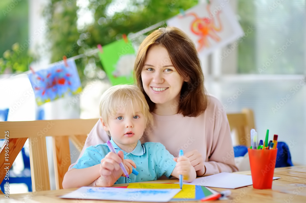 Cute little boy drawing and painting with colorful markers pens at kindergarten Cute little boy drawing and painting with colorful markers pens at kindergarten
