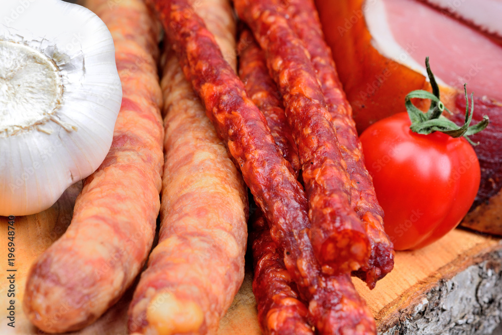 Sausages with prosciutto crudo and garlic and cherry tomatoes on a wood cutting board Sausages with prosciutto crudo and garlic and cherry tomatoes on a wood cutting board
