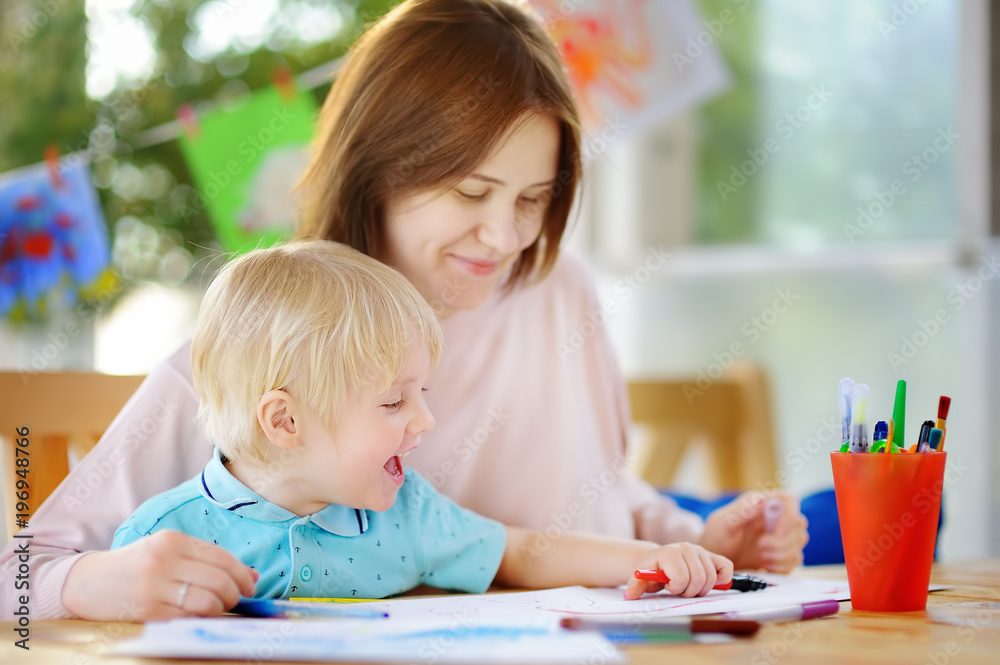 Cute little boy drawing and painting with colorful markers pens at kindergarten