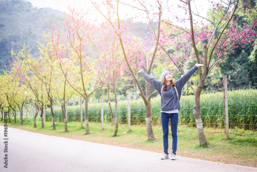 Happy woman traveler relax feel free with cherry blossoms or sakura flower tree on vacation Happy woman traveler relax feel free with cherry blossoms or sakura flower tree on vacation