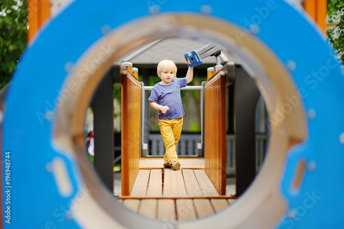 Little boy having fun on outdoor playground/on slide