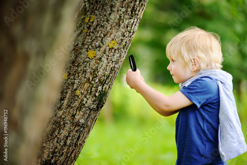 Charming kid exploring nature with magnifying glass