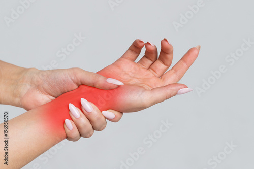 Female arms holding her painful wrist caused by prolonged work on the computer, laptop, coloured in red. Carpal tunnel syndrome, arthritis, neurological disease , numbness of the hand