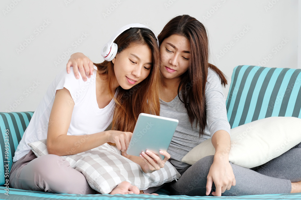 Young cute asia lesbian couple using tablet with happiness at home, lgbt, homosexual, lesbian couple lifestyle Young cute asia lesbian couple using tablet with happiness at home, lgbt, homosexual, lesbian couple lifestyle