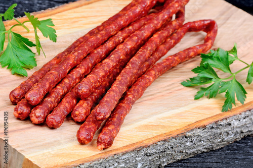 Heap of sausages with parsley on wooden board