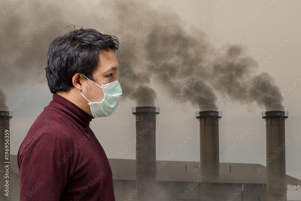 Plakat Asian man wearing the face mask against air pollution with hand catching the headache over over the Smokestack Factory with black smoke on the sky with cloud, healthcare industry and pollution concept