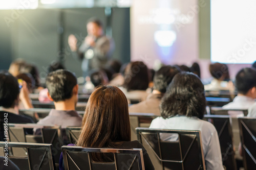 Rear view of Audience in the conference hall or seminar meeting which have speaker in front of the room on the stage, business and education concept