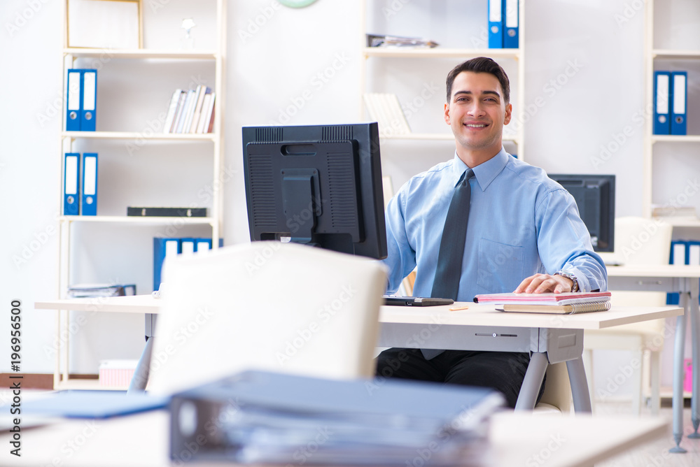 Handsome businessman employee sitting at his desk in office Handsome businessman employee sitting at his desk in office