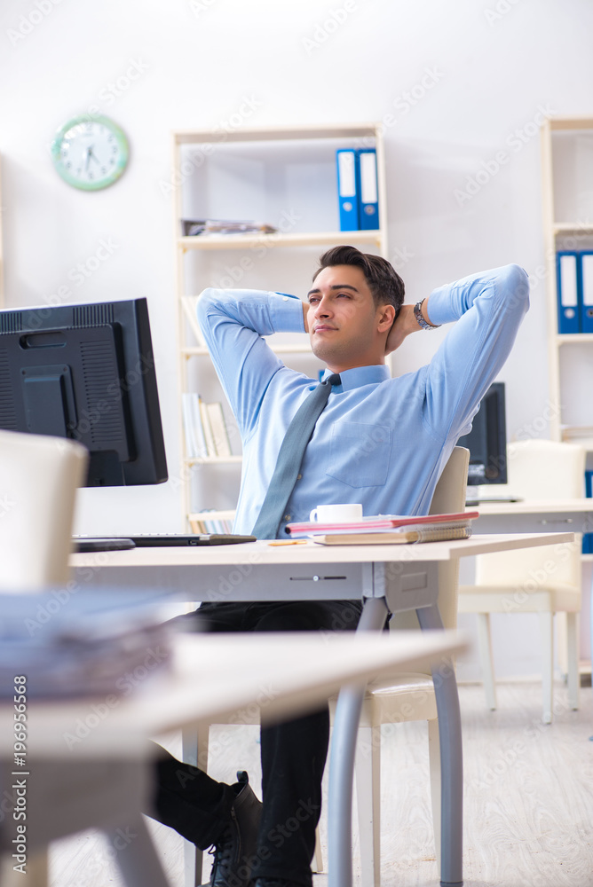 Handsome businessman employee sitting at his desk in office Handsome businessman employee sitting at his desk in office