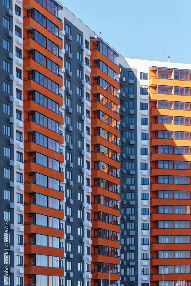 A multi-storey residential building painted in different colors against the blue sky, a freshly constructed one is waiting for new tenants to enter it