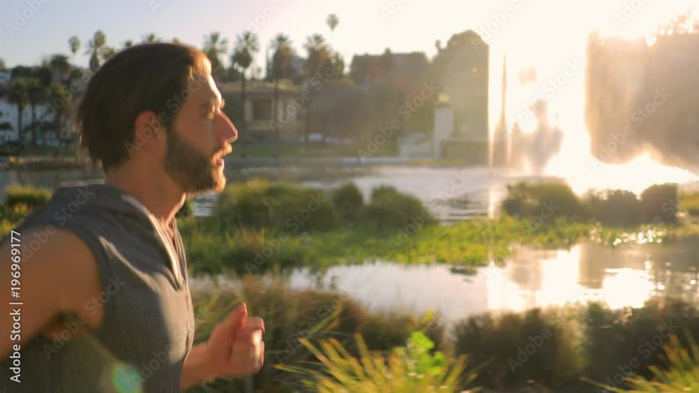 Athletic man jogs around a small lake in Los Angeles.