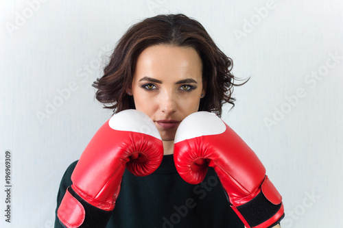 serious pretty brunette woman with red boxing gloves looking at the camera