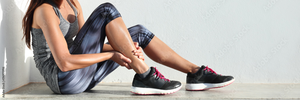 Fototapeta Biegi sportowe kontuzji nogi ból - biegacz kobieta biegacz boli trzymając bolesne skręcenie mięśni kostki. Lekkoatletka z bólem stawów lub mięśni i problem z bólem panoramy banner.