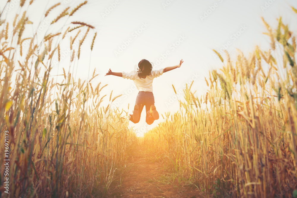 Back view of jumping girl in the barley farm.Freedom concept. - obrazy, fototapety, plakaty 