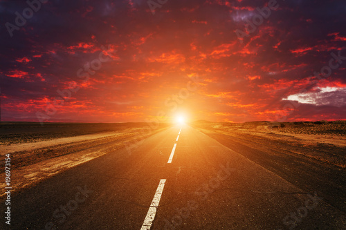 Fototapeta Naklejka Na Ścianę i Meble -  Picturesque fiery sunset over the cracked desert road