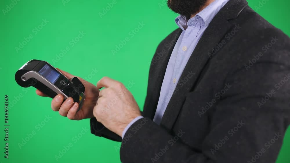 Man makes a payment with nfc ring, NFC terminal, green background.
Man makes a payment with nfc ring, NFC terminal, green background.