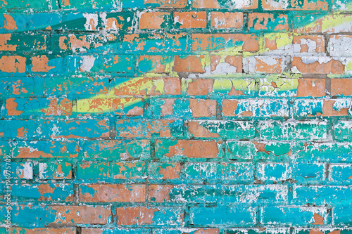 Old colorful  turquoise and yellow  paint with cracks on red brick wall as background  texture