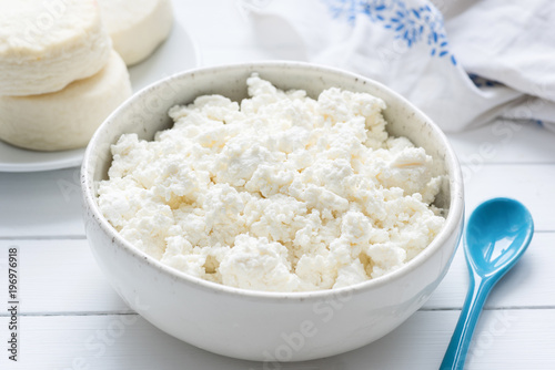 Tvorog, farmers cheese, curd cheese or cottage cheese in white bowl on white wooden table, closeup view. Rich in calcium healthy food