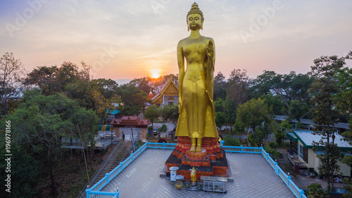 aerial photography the golden big Buddha standing statue on hilltop in sunset time at wat Phra That Jom Wae in Chiang Rai Thailand