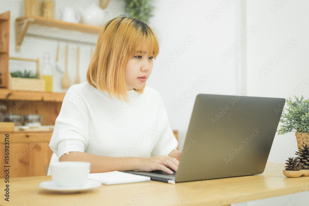 Beautiful young smiling Asian woman working on laptop while at home in office work space. Businesswoman working from home via portable computer writing on keyboard. Enjoying time at home. Beautiful young smiling Asian woman working on laptop while at home in office work space. Businesswoman working from home via portable computer writing on keyboard. Enjoying time at home.