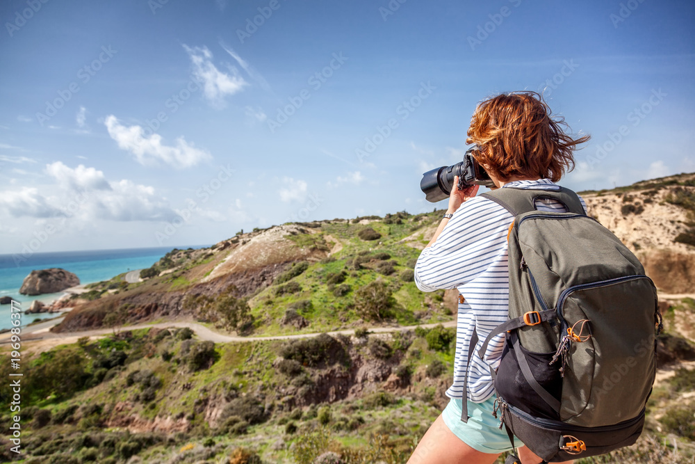 young woman traveler with a camera in the hands of a background of stunning scenery, travel, hiking, unity with nature, freedom and vacations concept