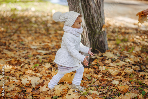 Child in autumn orange leaves.