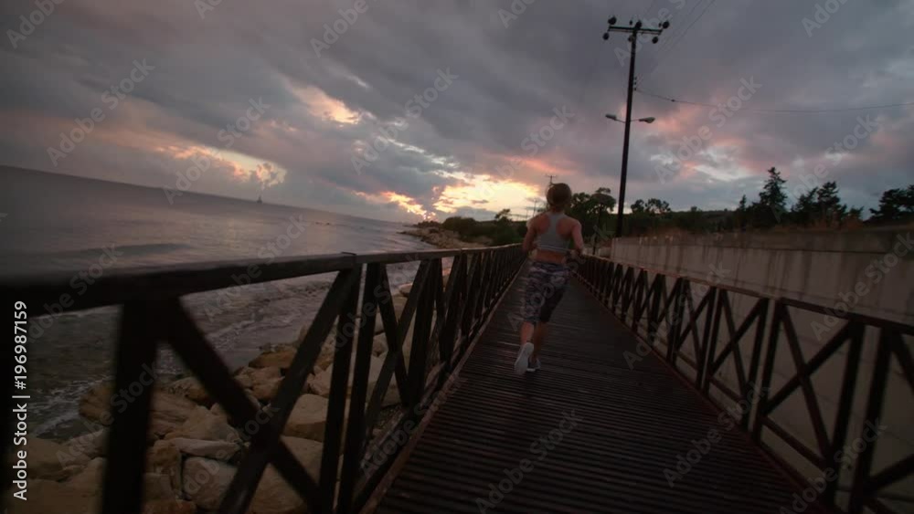 Woman jogging on pier at sunset Woman jogging on pier at sunset