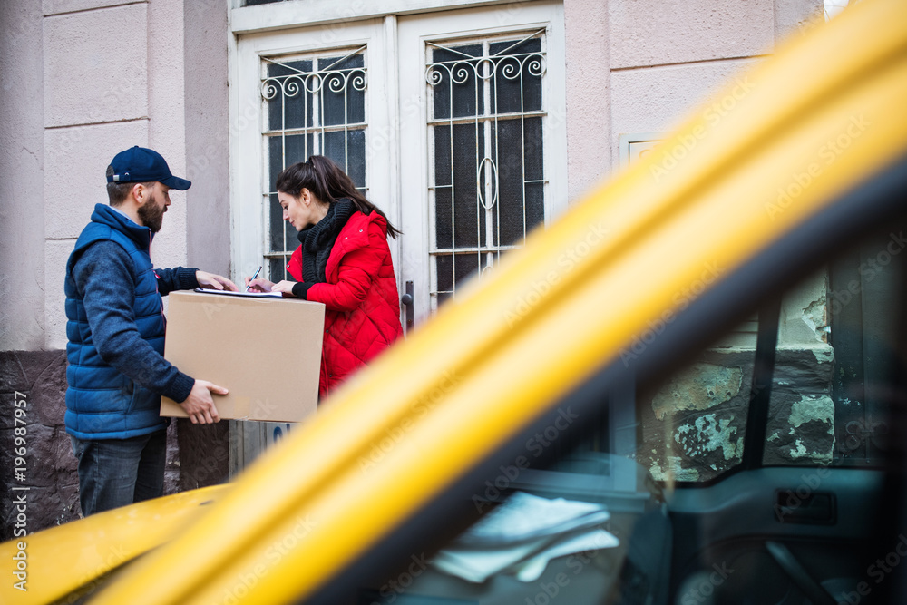 Woman receiving parcel from delivery man at the door.