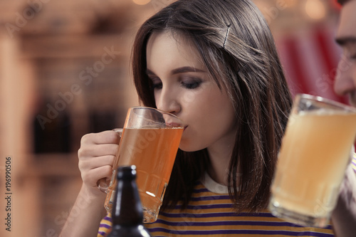 Woman drinking beer in sport bar