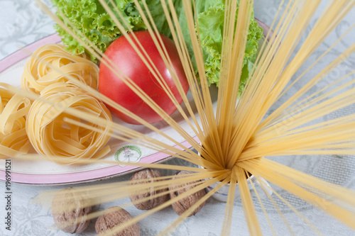 still life with fettuccine, spaghetti, nuts, tomato leaves and lettuce leaves