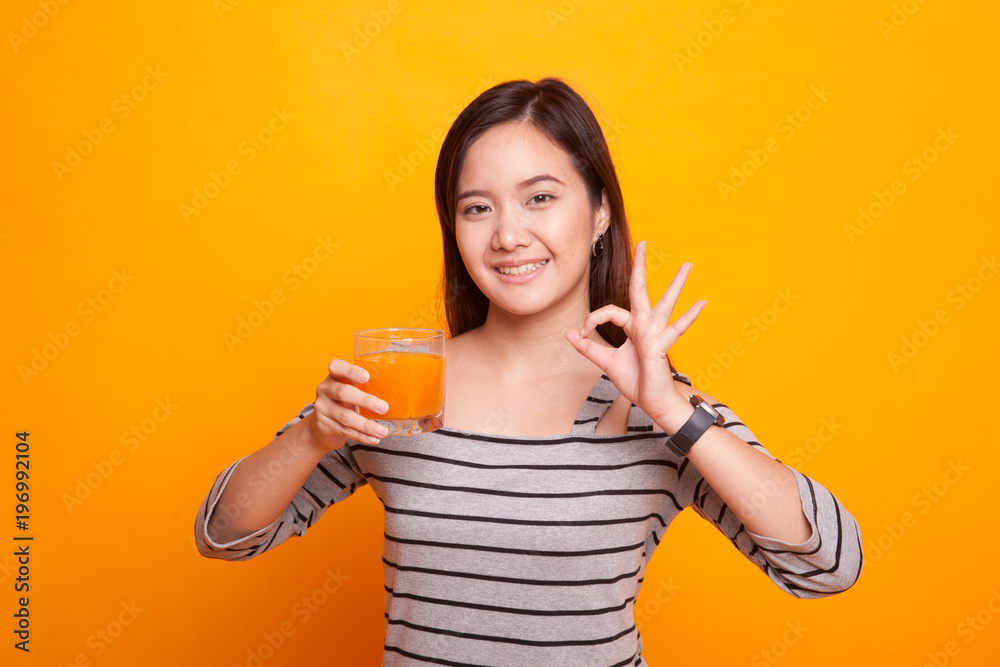 Young Asian woman drink orange juice show OK sign. Young Asian woman drink orange juice show OK sign.