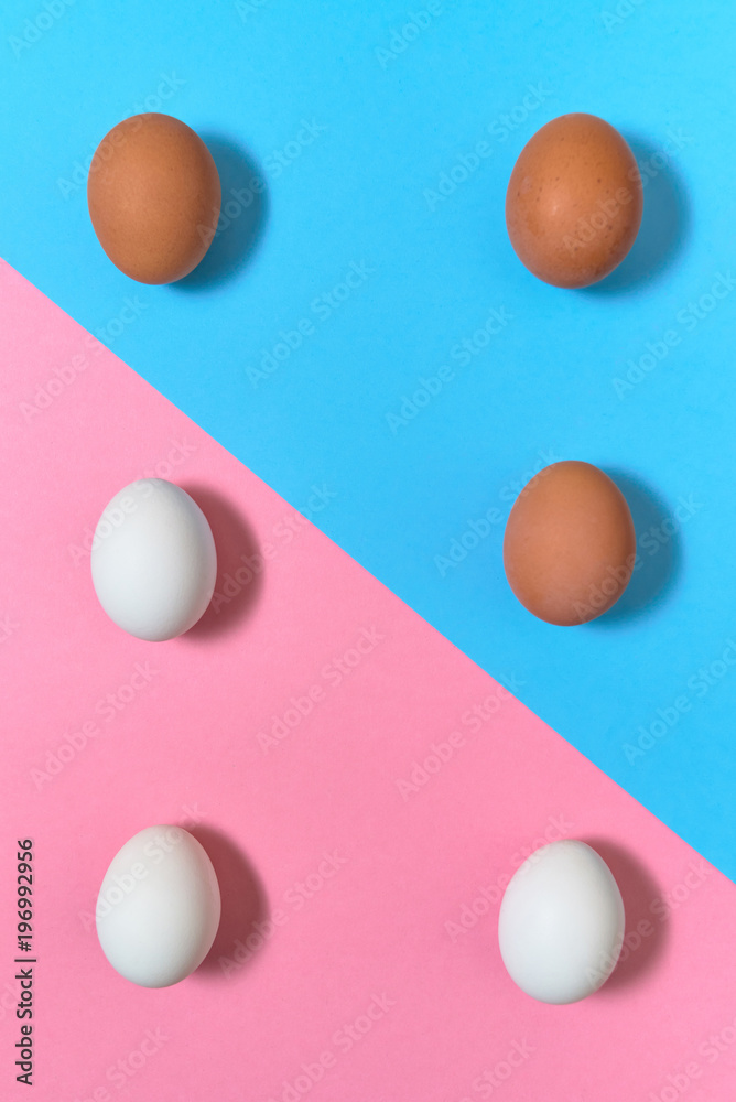 White and brown eggs on blue and pink pastel background, copy space. Boiled eggs on paper background with two tone color. Healthy food concept. Easter eggs. Flat lay, top view White and brown eggs on blue and pink pastel background, copy space. Boiled eggs on paper background with two tone color. Healthy food concept. Easter eggs. Flat lay, top view