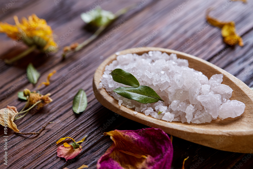 SPA concept: composition of spa treatment with natural sea salt, aromatic oil and flowers on wooden background SPA concept: composition of spa treatment with natural sea salt, aromatic oil and flowers on wooden background