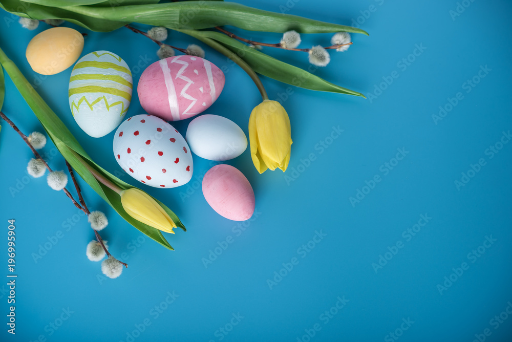 Fototapeta premium Colorful Easter eggs with yellow Tulip hand painted on a blue background. Holiday spring card